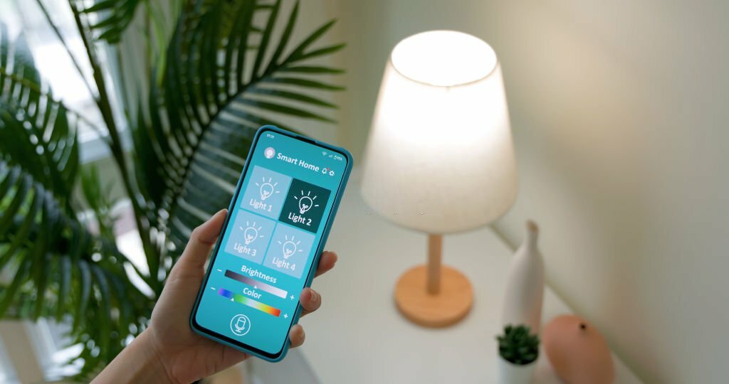 smart home concept - asian woman using app to turn on lamp by mobile phone at home